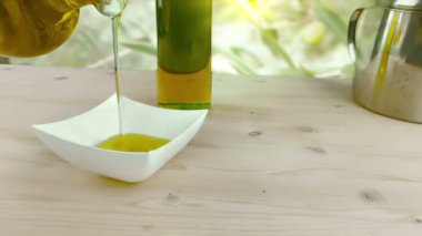 zeytinyağı şişesi, yakınındaki ahşap masa arka plan üzerinde beyaz kap içinde şişede pişirme zeytin yağ boşaltma açık, sağlıklı gıda beslenme kavramı ağır çekimde vurulmuş 