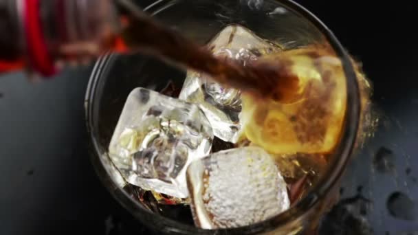 Сверху вид заливки свежей колы в стакан напитка с кубиками льда на черном фоне, веселье и летнее время — стоковое видео