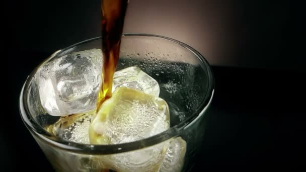 Vertido de coque fresco en el vaso de bebida con cubitos de hielo sobre fondo negro, diversión y hora de verano — Vídeos de Stock