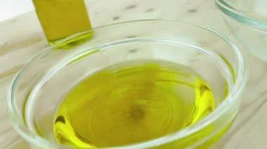 pişirme zeytin yağı damla ile beyaz kapsayıcısında şişe zeytinyağı şişesi yakınındaki ahşap masa arka plan üzerinde dökme, beyaz, sağlıklı gıda beslenme kavramı üzerinde ağır çekimde atış 