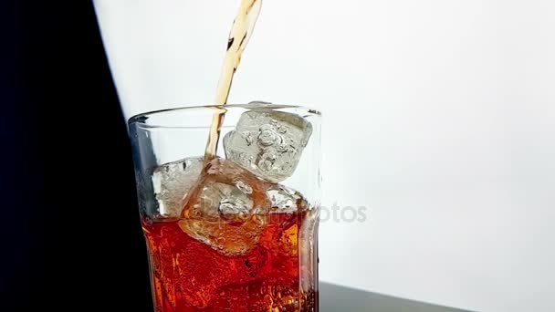 Pouring orange drink alcohol cocktail into the glass with ice cubes on black background — Stock Video