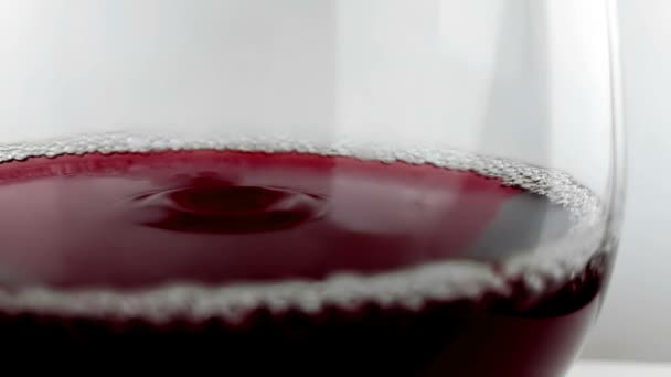 Падение красного вина в бокал для питья на белом фоне, концепция питания здравоохранения, съемка с высокой скоростью камеры — стоковое видео