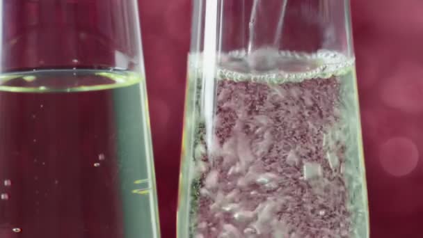 Close-up van het fluiten van champagne vullen met gouden bubbels tegen rode bokeh achtergrond, concept van gouden luxe vakantie valentine dag liefdesrelatie — Stockvideo