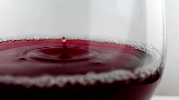 红葡萄酒下落入饮料玻璃在白色背景 营养健康关心概念 射击用高速照相机在慢动作 — 图库视频影像