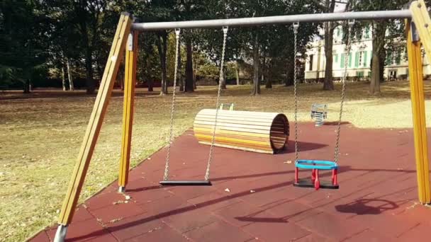 Columpios vacíos con cadenas balanceándose en el patio de recreo para el niño, movido del viento, lento — Vídeos de Stock