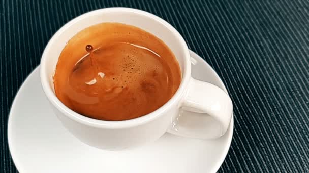 Coffee drop falling in super slow motion inside of cup of espresso italian coffee with foam on black background, food and drink — Stock Video