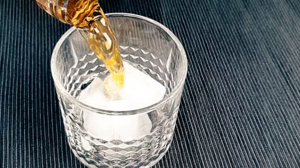 Barman menuangkan wiski di kaca dengan es batu di atas meja, fokus pada es batu, wiski bersantai waktu pada hangat — Stok Video