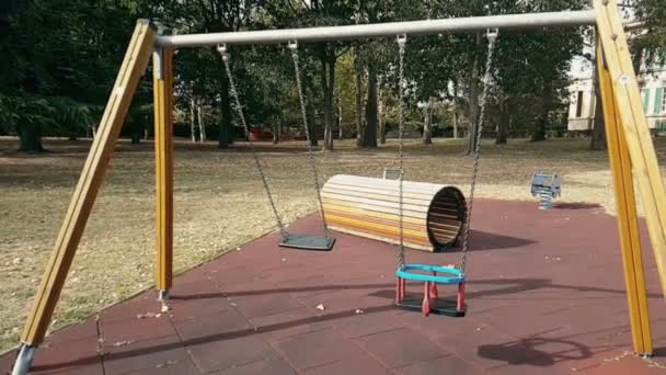 Leere Schaukeln mit Ketten, die auf Spielplatz schaukeln — Stockvideo