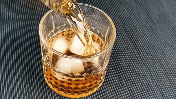 Barman verter whisky en el vaso con cubitos de hielo en la mesa, centrarse en los cubitos de hielo, whisky relajarse tiempo en caliente — Vídeos de Stock