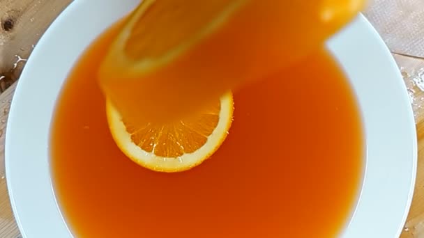 Super slow motion shot of orange slice falling down splashing to orange — Stock Video