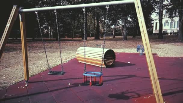 Puste huśtawki z łańcuchami kołyszącymi się na placu zabaw dla dzieci, poruszane od wiatru, powoli — Wideo stockowe