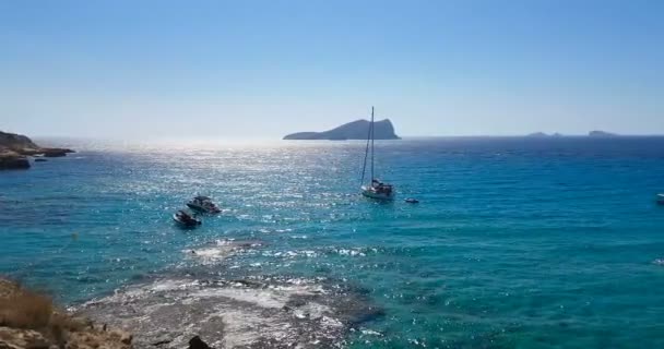Piękna plaża w świetle dnia z spokojnym morzem, latem bardzo popularne, piaszczyste wybrzeże mają fantastyczny widok na wyspę Ibiza. Zacumowany — Wideo stockowe