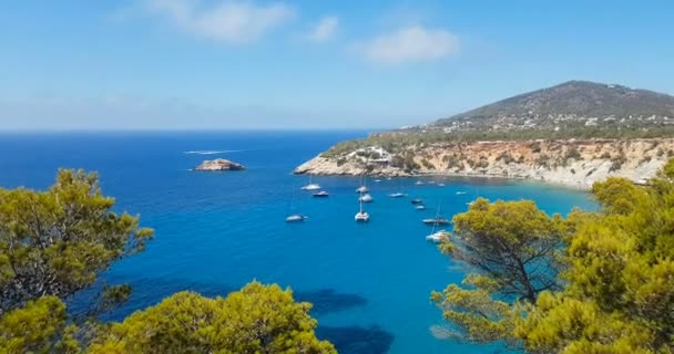 Pantai yang indah di siang hari dengan laut tenang, di musim panas sangat populer, pantai berpasir memiliki pemandangan pulau ibiza yang fantastis. Ditambatkan — Stok Video