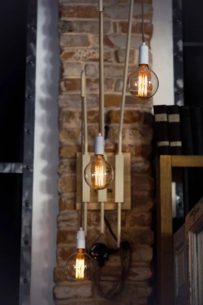 torch with three lit lamps on brick wall near book shelf