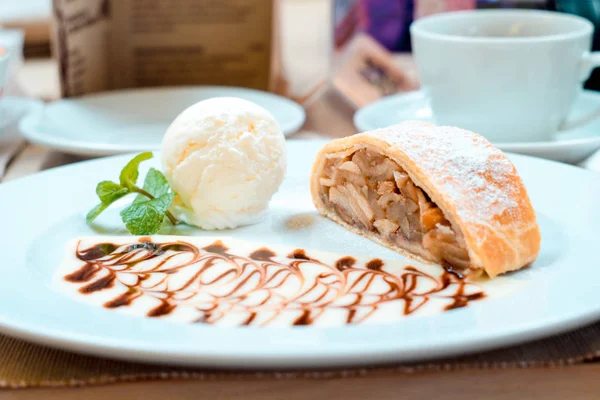 Vanilyalı dondurma siyah ve beyaz çikolata ile beyaz bir tabak üzerinde elma strudel puf böreği güzel bir resim şeklinde plaka üzerine dökülen