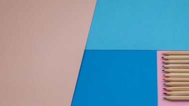 Renkli kalemlerle renklendirilmiş pembe ve mavi renkli kâğıt arkaplanlı çok renkli kalemler. Siyah arka planda renkli kalemler yığını. Kavram: Hayata boş bir sayfa ile başla.