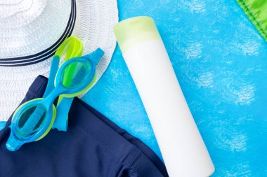 Yaz aksesuarları. Mavi desenli arka planda gözlük, yüzme şortu ve diğerleri. Üst görünüm ve kopyalama alanı