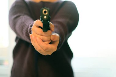 Evde elinde silah tutan bir kadın. Gri arka planda siyah silah kullanan genç kadınlara odaklan..