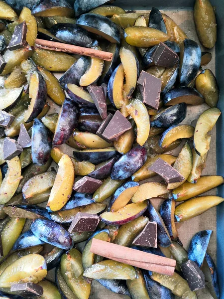 Verse pruimenvruchten in plakjes gesneden, plakjes met kaneelstokjes, chocolade, kruidnagel. Bereiding van ingrediënten en fruit voor het maken van heerlijke jam. — Stockfoto