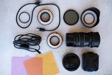Grideki profesyonel fotoğrafçı için düz kompozisyon ekipmanı. Fotoğraf gradyan filtresi, makro halkalar, polarize filtre, şarj aleti, renkli plakalı video ışığı, kameralar için lens kapakları