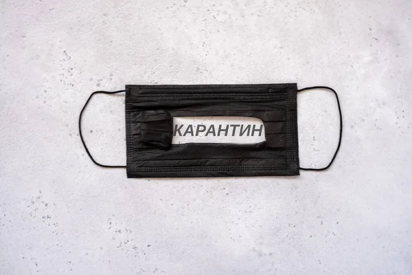 Medical protective disposable black mask with text on the slot in Russian meaning the word quarantine in dark grey. concept protection of dangerous 2019-nCoV — Stok fotoğraf