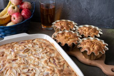 Turta ya da elmalı kek ve mutfakta çay olan bej ahşap tahta tahta. Koyu arkaplanda bir tabakta kırsal elmalar. konsept-sonbahar hasat yemekleri