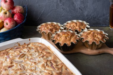 Turta ya da elmalı kek ve mutfakta çay olan bej ahşap tahta tahta. Koyu arkaplanda bir tabakta kırsal elmalar. konsept-sonbahar hasat yemekleri
