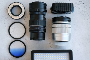 Video ışığı, lens filtreleri, polarizör, gradyan ve adaptör halkaları, ve gri arka grond üzerinde flash diskleri olan bir kutu. Profesyonel fotoğrafçı için ekipmanla düz kompozisyon
