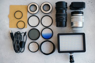 Video ışığı, lens filtreleri, polarizör, gradyan ve adaptör halkaları, ve gri arka grond üzerinde flash diskleri olan bir kutu. Profesyonel fotoğrafçı için ekipmanla düz kompozisyon