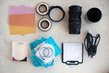 Video ışığı, lens filtreleri, polarizör, gradyan ve adaptör halkaları, ve gri arka grond üzerinde flash diskleri olan bir kutu. Profesyonel fotoğrafçı için ekipmanla düz kompozisyon