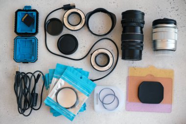 Video ışığı, lens filtreleri, polarizör, gradyan ve adaptör halkaları, ve gri arka grond üzerinde flash diskleri olan bir kutu. Profesyonel fotoğrafçı için ekipmanla düz kompozisyon