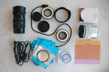 Video ışığı, lens filtreleri, polarizör, gradyan ve adaptör halkaları, ve gri arka grond üzerinde flash diskleri olan bir kutu. Profesyonel fotoğrafçı için ekipmanla düz kompozisyon