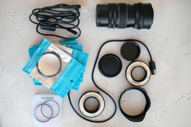Video ışığı, lens filtreleri, polarizör, gradyan ve adaptör halkaları, ve gri arka grond üzerinde flash diskleri olan bir kutu. Profesyonel fotoğrafçı için ekipmanla düz kompozisyon