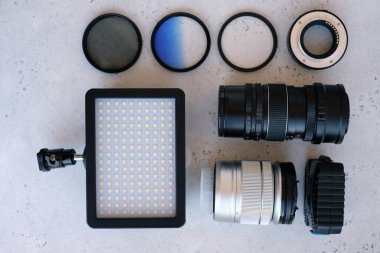 Video ışığı, lens filtreleri, polarizör, gradyan ve adaptör halkaları, ve gri arka grond üzerinde flash diskleri olan bir kutu. Profesyonel fotoğrafçı için ekipmanla düz kompozisyon