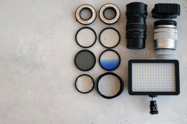 Video ışığı, lens filtreleri, polarizör, gradyan ve adaptör halkaları, ve gri arka grond üzerinde flash diskleri olan bir kutu. Profesyonel fotoğrafçı için ekipmanla düz kompozisyon