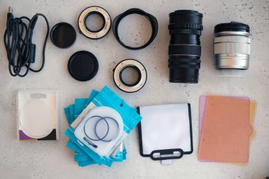 Video ışığı, lens filtreleri, polarizör, gradyan ve adaptör halkaları, ve gri arka grond üzerinde flash diskleri olan bir kutu. Profesyonel fotoğrafçı için ekipmanla düz kompozisyon