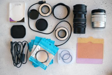 Video ışığı, lens filtreleri, polarizör, gradyan ve adaptör halkaları, ve gri arka grond üzerinde flash diskleri olan bir kutu. Profesyonel fotoğrafçı için ekipmanla düz kompozisyon