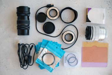 Video ışığı, lens filtreleri, polarizör, gradyan ve adaptör halkaları, ve gri arka grond üzerinde flash diskleri olan bir kutu. Profesyonel fotoğrafçı için ekipmanla düz kompozisyon