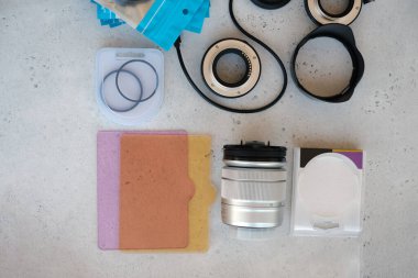 Video ışığı, lens filtreleri, polarizör, gradyan ve adaptör halkaları, ve gri arka grond üzerinde flash diskleri olan bir kutu. Profesyonel fotoğrafçı için ekipmanla düz kompozisyon