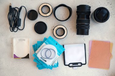 Video ışığı, lens filtreleri, polarizör, gradyan ve adaptör halkaları, ve gri arka grond üzerinde flash diskleri olan bir kutu. Profesyonel fotoğrafçı için ekipmanla düz kompozisyon