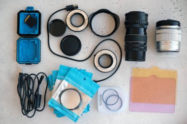 Video ışığı, lens filtreleri, polarizör, gradyan ve adaptör halkaları, ve gri arka grond üzerinde flash diskleri olan bir kutu. Profesyonel fotoğrafçı için ekipmanla düz kompozisyon