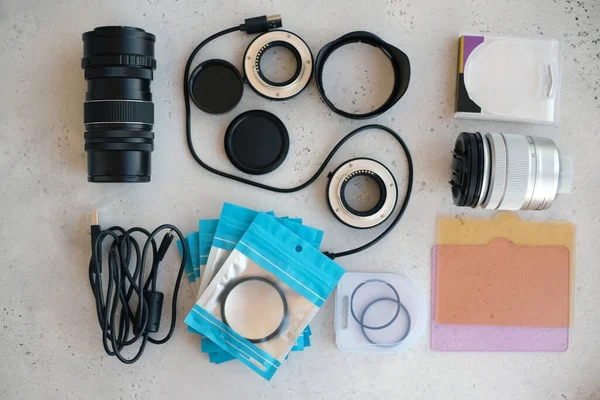 Video ışığı, lens filtreleri, polarizör, gradyan ve adaptör halkaları, ve gri arka grond üzerinde flash diskleri olan bir kutu. Profesyonel fotoğrafçı için ekipmanla düz kompozisyon