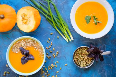 . Top View, ayçiçeği tohumları ve yeşil soğan, mavi arkaplanda servis kasesinde mor fesleğen. Mavi arka planda mor fesleğenli balkabağı çorbası.