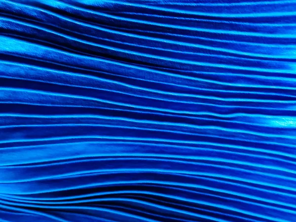 Textura, fundo, padrão, pano azul plissado. Um brilhante tecido de cetim dobrado acabado é uma luz . — Fotografia de Stock
