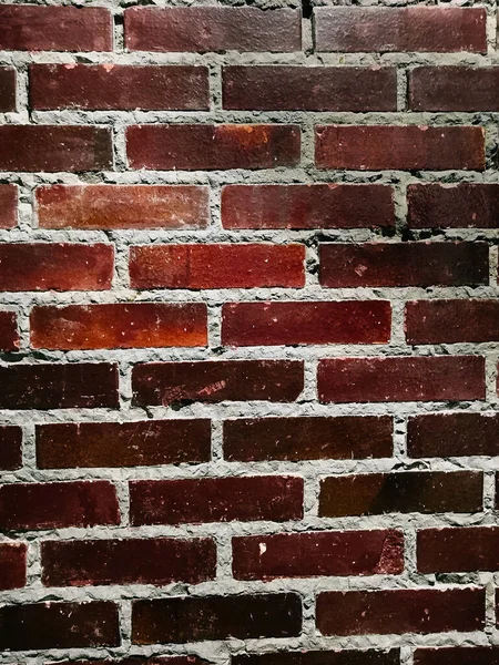 smooth wall of dark red brick. Red brick wall background. Texture of a brick wall with cracks and scratches.