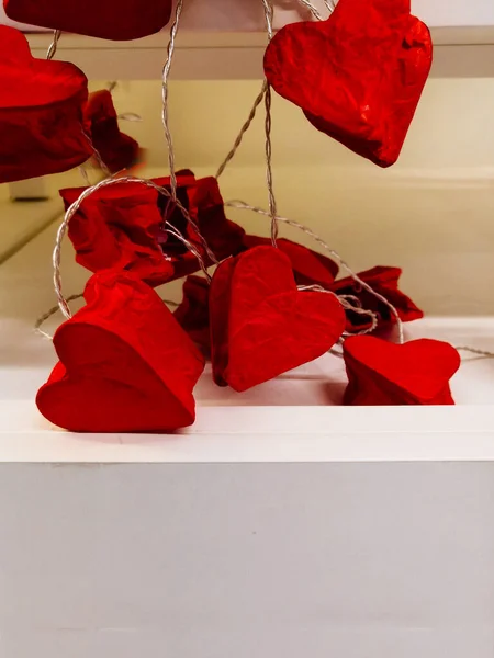 lamps on a wire in the form of hearts.. repairing garland in the form of red hearts. Valentine\'s day decoration concept