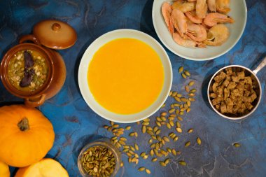 Kavanozda kabak çorbası, kızarmış ekmek dilimleri ve mor fesleğenle süslenmiş kabak tohumları.