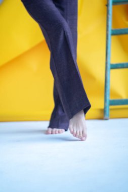 Genç, rahat bir kadın, arka planda sarı bir duvarla yerde yalınayak yürüyor. konfor kavramı, metin için sıcak zemin alanı