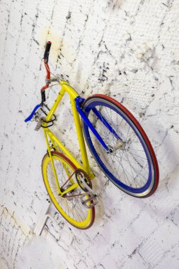 Duvarda asılı çok renkli bisiklet, sarı, mavi ve kırmızı renklerin farklı ayrıntıları. Çatı katı tarzında motor deposu