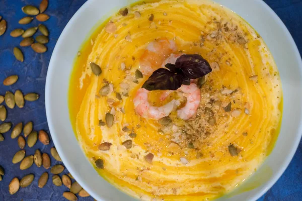 Tasty pumpkin cream soup with shrimps and basil leaves, blended with spice and carrots. Top view. — Stock Image Tasty Pumpkin Cream Soup Shrimps Basil Leaves Blended Spice Carrots Stock Picture